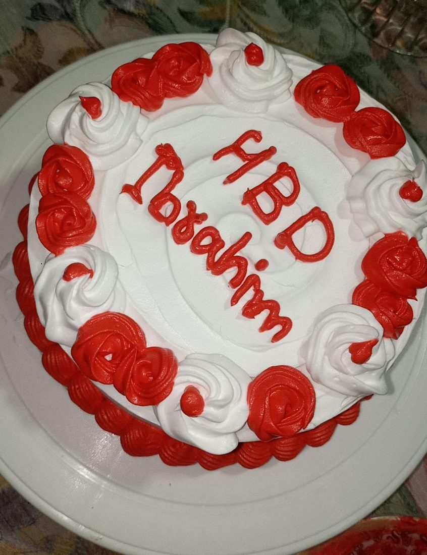 White cake with red rosettes and a birthday message