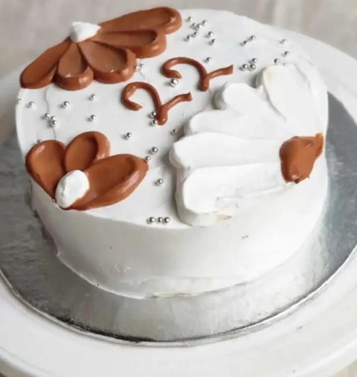 White-frosted cake with chocolate pieces arranged on top and a message