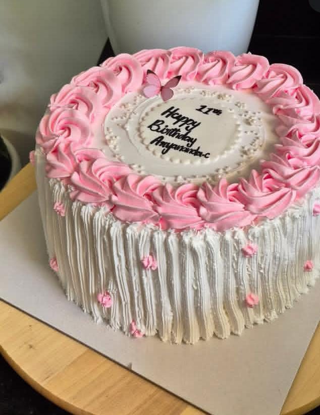 White cake with a pink piped border and a message written in the centre