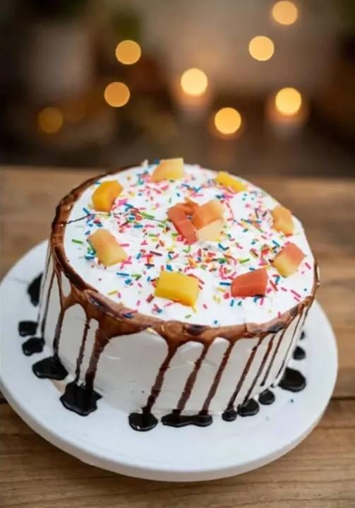 Round cake with light frosting, chocolate drip and colourful sprinkles